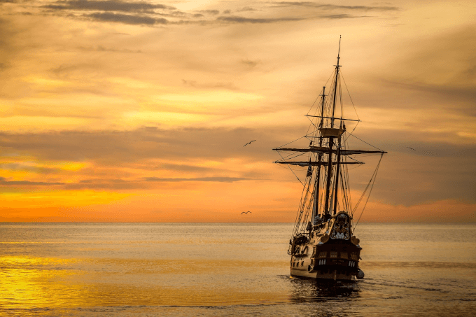 Old fashioned pirate ship sailing into the sunset